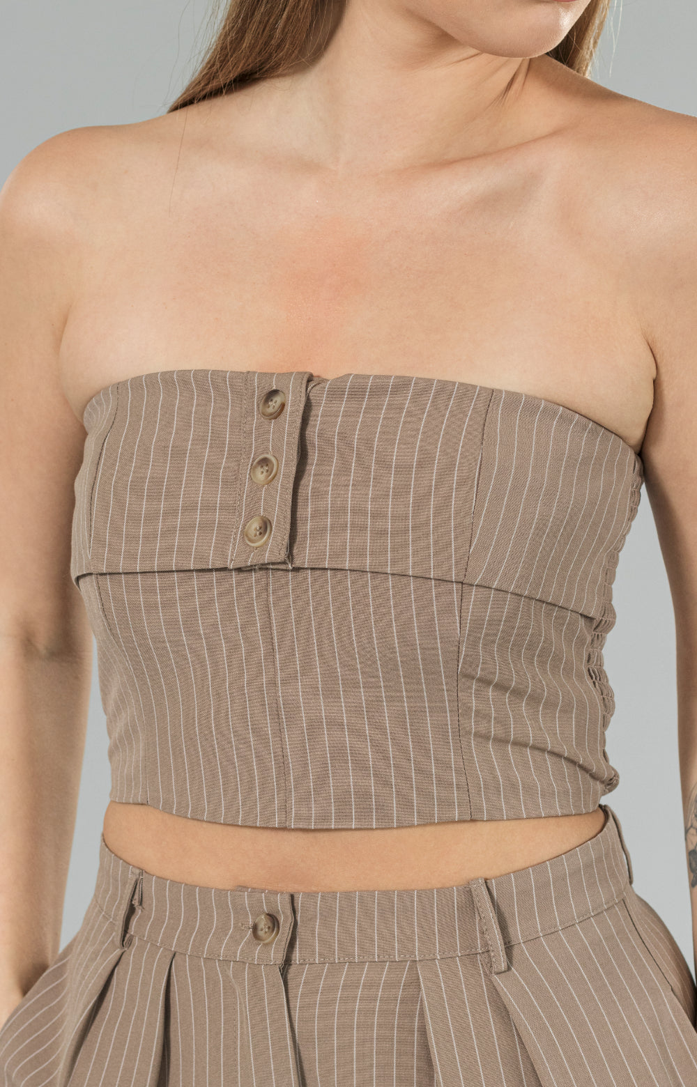 Introducing our Beeta crop top, designed to keep you comfortable and stylish all day long. Made with smocking at the back for an easy and adjustable fit, this crop top is perfect fitted tube top for any occasion. The button details at the center front add a touch of elegance, while the beautiful mocha and white stripe pattern adds a chic and modern touch. 