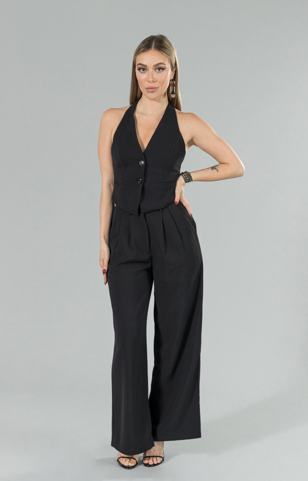 Introducing our Mia halter neck vest, perfect for any occasion! This stylish halter top features buttons at the center front, adding a unique touch to the design. Whether you're dressing up for a night out or keeping it casual for a day at the office, this versatile vest top has got you covered. Its halter style neckline adds a touch of elegance, making it a must-have item for your wardrobe.